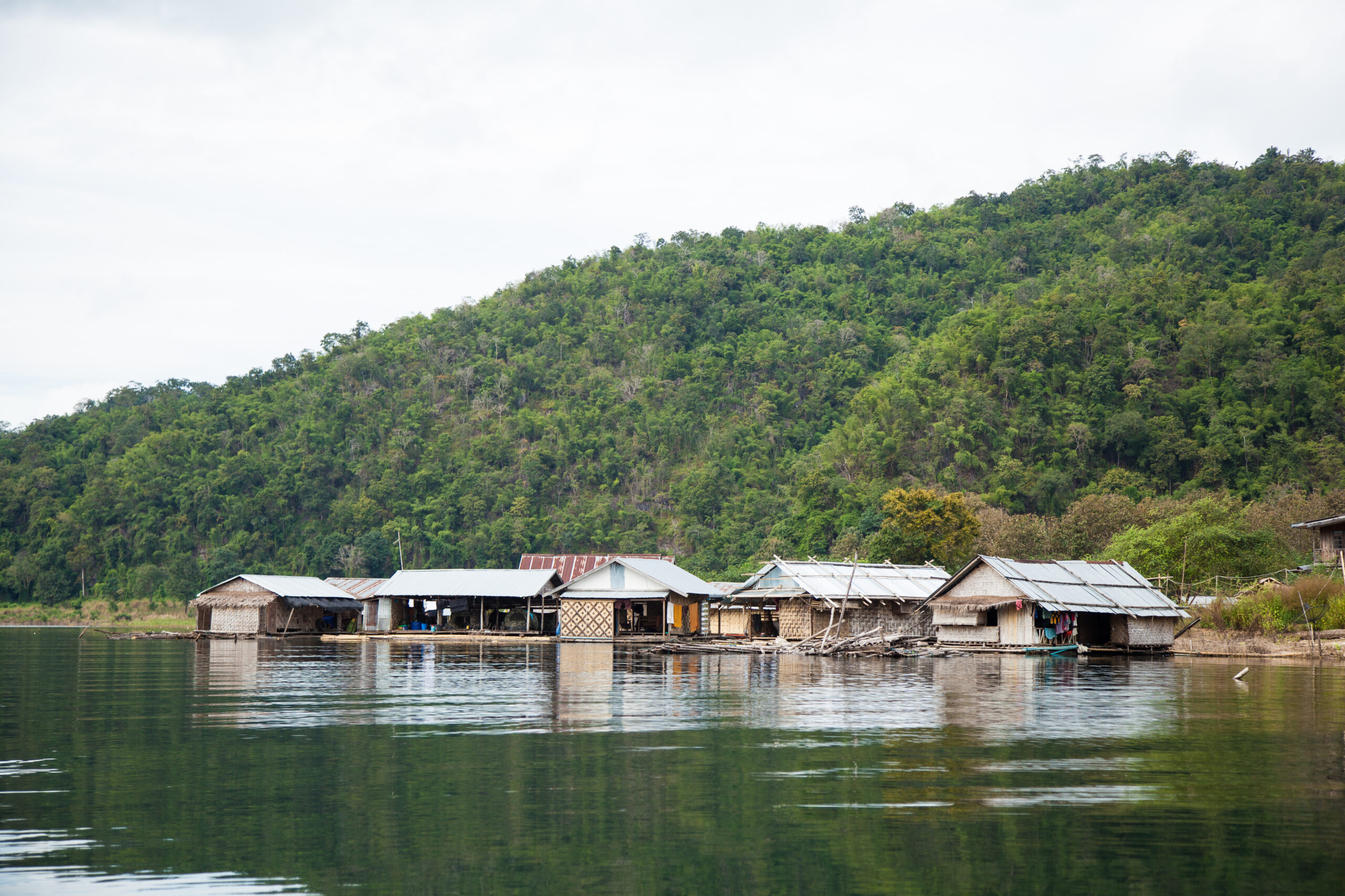 Na imagem há o Rio Amazonas, com mata aberta ao fundo e casas bem simples que estão fincadas dentro do rio.